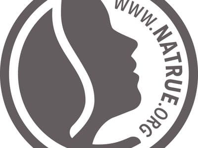 Logo mit einem stilisierten Frauenprofil in einem Kreis und der Webadresse www.natrue.org, die den Kreis umrundet.